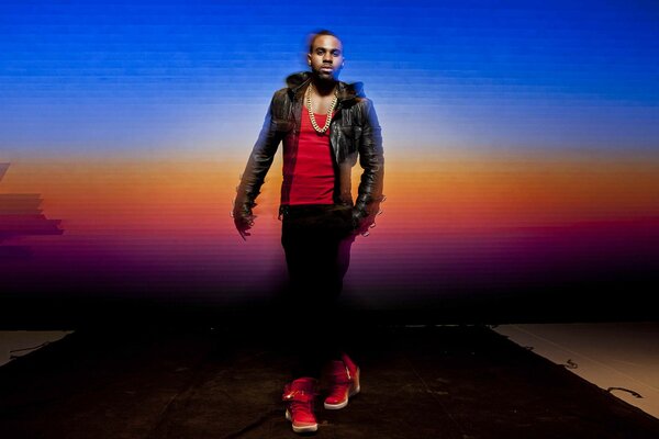 Musicien afro-américain en t-shirt rouge, baskets et veste sur fond arc-en-ciel