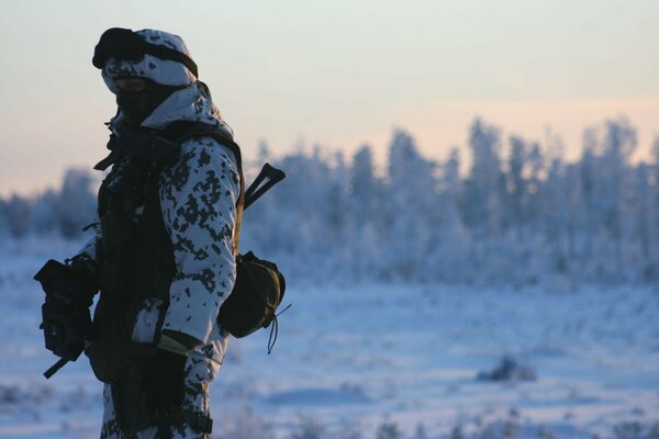 A man in camouflage on the background of a winter landscape