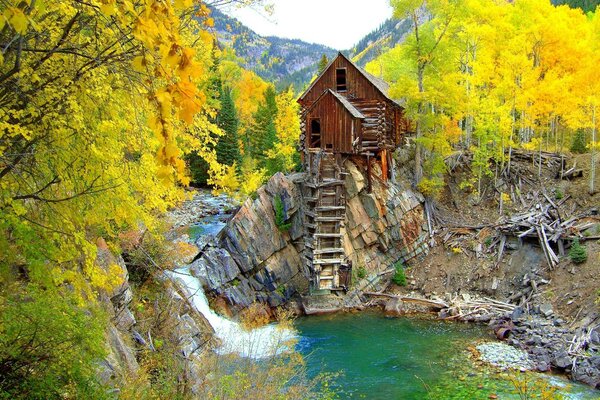 Holzhaus auf einem Felsen inmitten eines Herbstwaldes