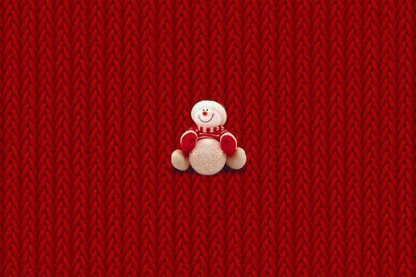 Плюшевый снеговик на красном плетёном фоне