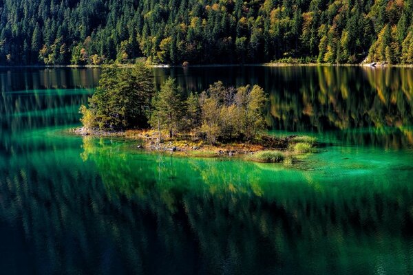 The landscape is a lake surrounded by a forest and in the middle is a small island