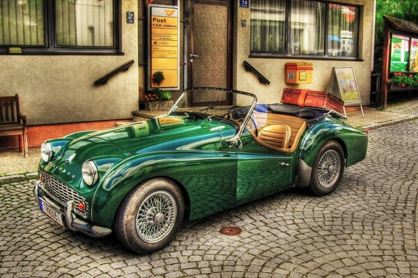 Convertible verde en adoquines cerca del edificio