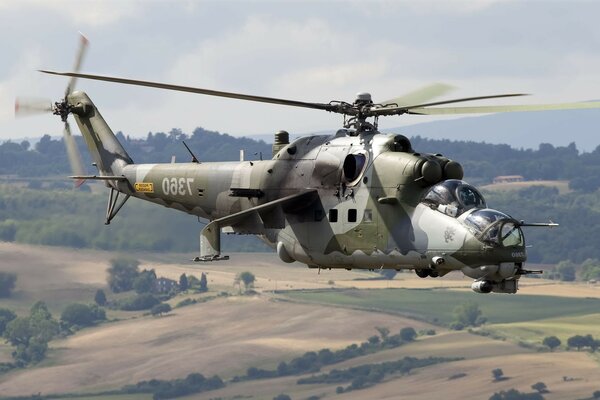 A military helicopter flies over the fields