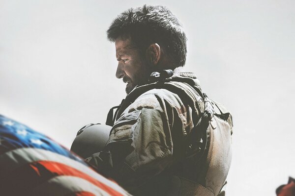 Homme triste en uniforme militaire près du drapeau américain