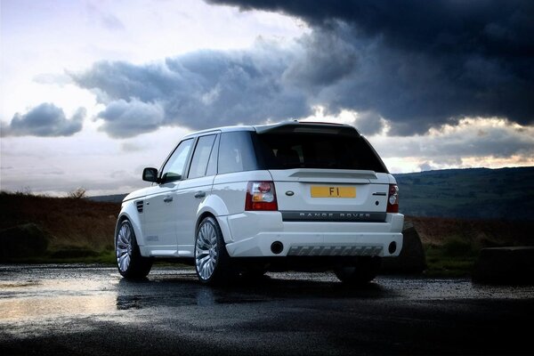 Range Rover auf nassem Asphalt vor einem Hintergrund von Wolken