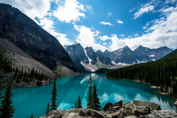 Blue mountain lake among the rocks. Blue sky with clouds