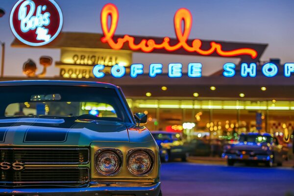 A car on the background of a neon cafe sign