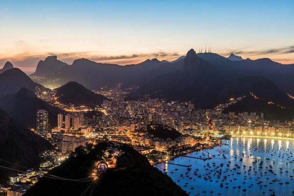 A bright sunset over a city glowing with lights in a mountainous area