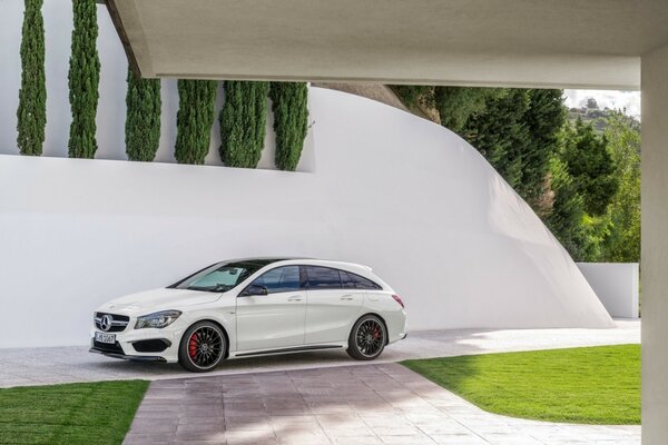 Auto mercedes-benz bianca nel cortile su sfondo muro bianco