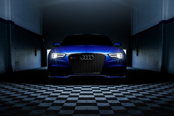 The headlights of a blue Audi