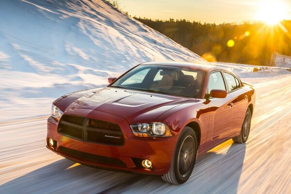 A red car is driving through the snow