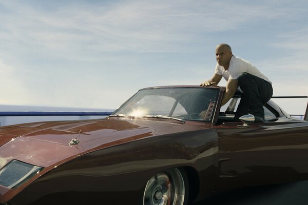 An actor in a car. A convertible. Clear sky