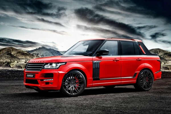 Red range rover on the background of the sky and mountains