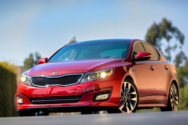 A red kia car. standing on an asphalt road