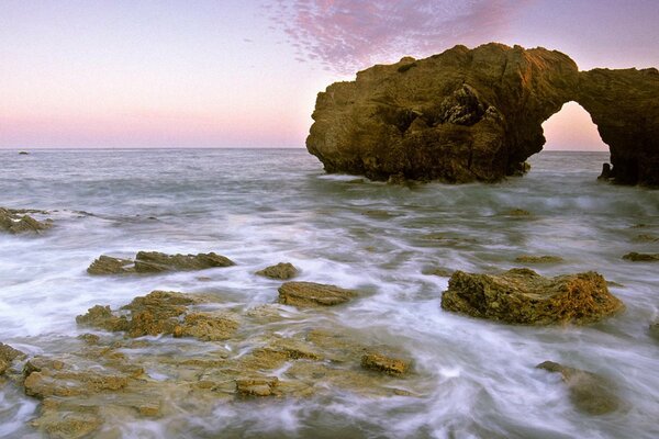 La spiaggia rocciosa illumina il tramonto rosa