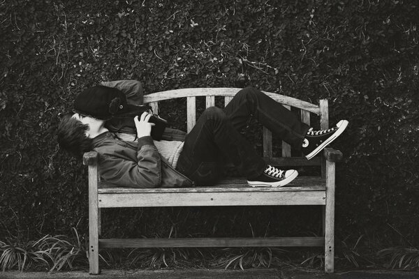 Black and white photo, a man lying on a bench