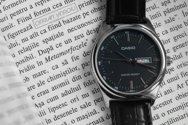 Une montre avec un cadran noir se trouve sur le livre