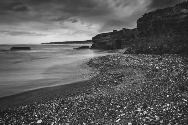 Strand mit Kieselsteinen und schlechtem Wetter