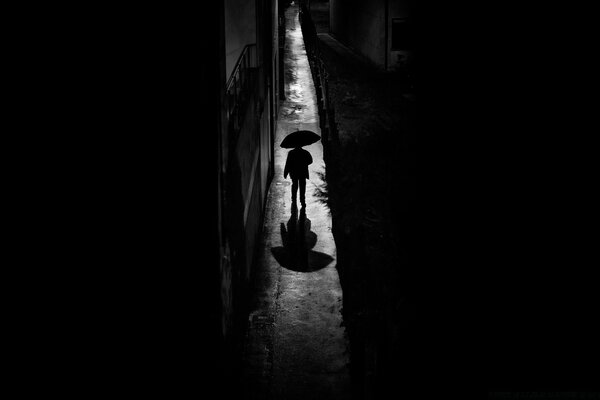 Silhouette of a man under an umbrella in black and white