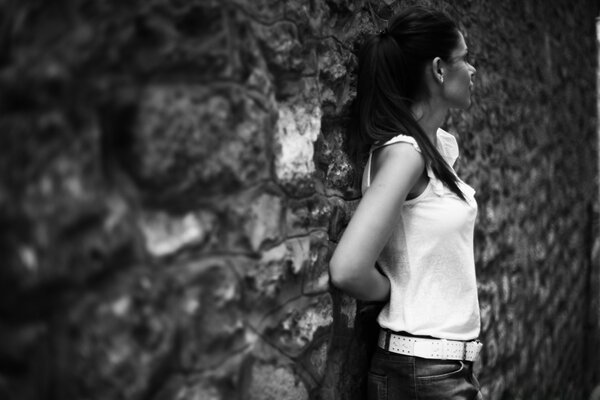 Monochrome portrait of a woman standing against the wall