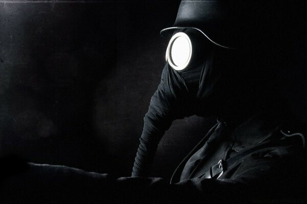 Black and white photo of a masked man on a dark background