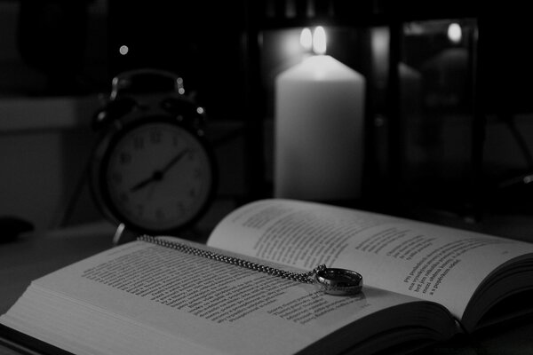 A black-and-white book lies next to a candle and a clock