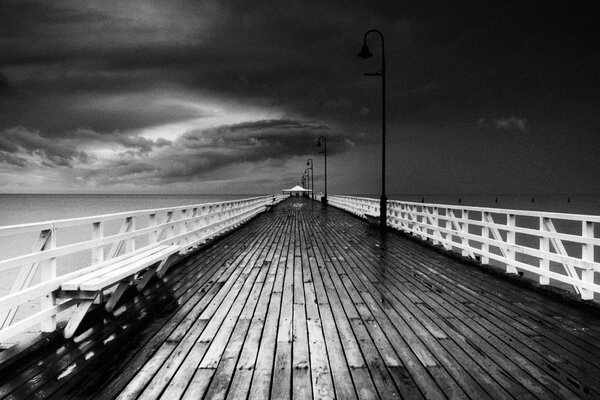 Wooden pier goes out to sea in black and white