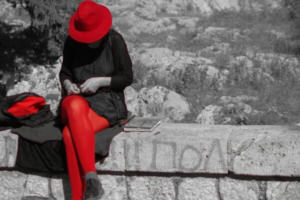 A girl in a hat sitting on a rock