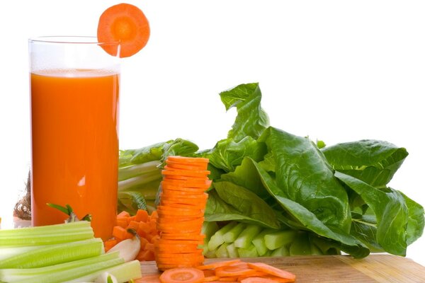 Verduras picadas en la mesa y un vaso de jugo de zanahoria