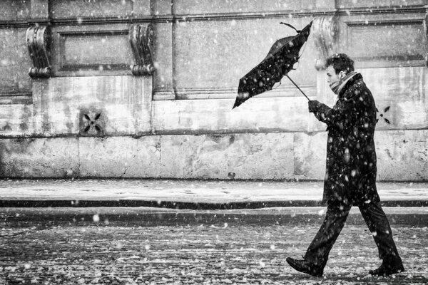 Schwarz-Weiß-Foto eines erwachsenen Mannes mit Regenschirm