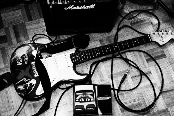 Amplifikatörün yanındaki ahşap zeminde yatan elektro gitar