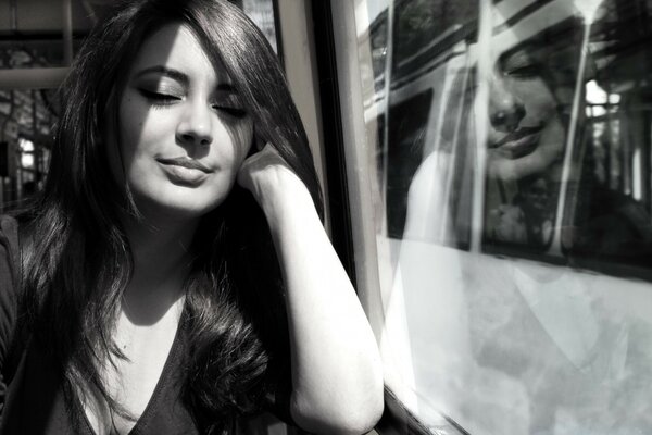 A girl with long hair is sitting near the window