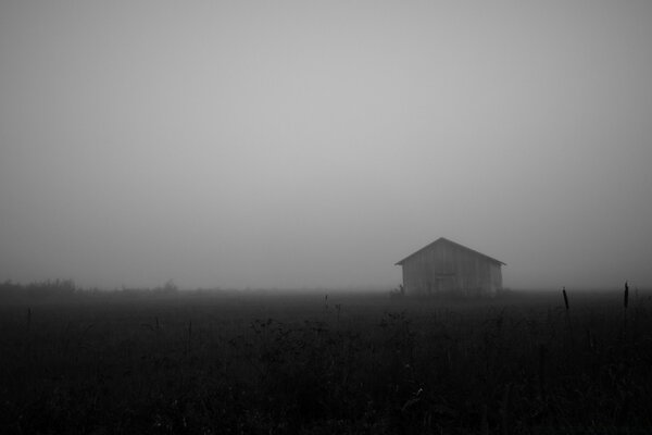 Black and white landscape of a barn in the fog