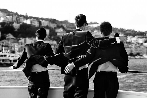 Three in black traveling on a yacht, catching the wind oncoming