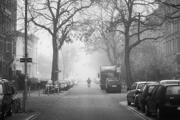 Un motociclista guida lungo la strada. ci sono macchine sul ciglio della strada