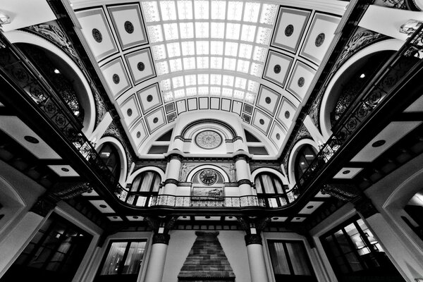 Clock on the wall of a huge hall in black and white