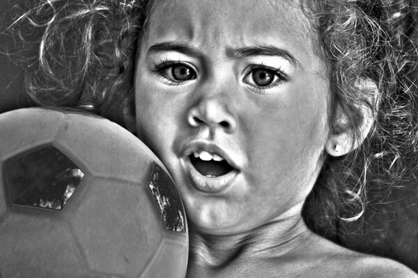 Black and white photo of a child with a ball