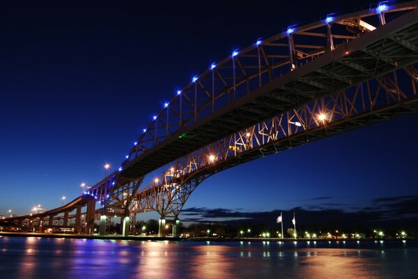 Illuminated bridge over the river at dusk