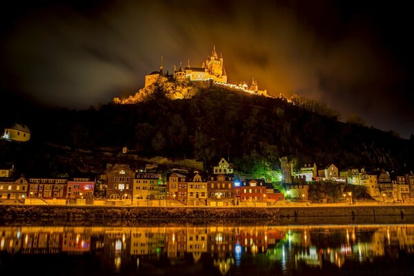 Burg beleuchtet auf einem Berg am Meer