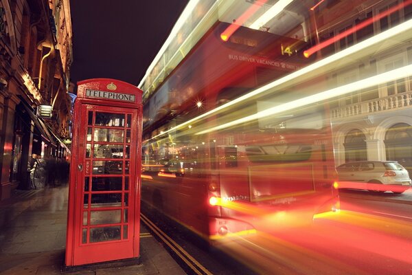 Cabina telefonica rossa e autobus in rapido movimento