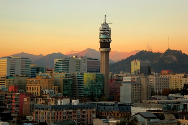 A city with a tower in the center and mountains in the background