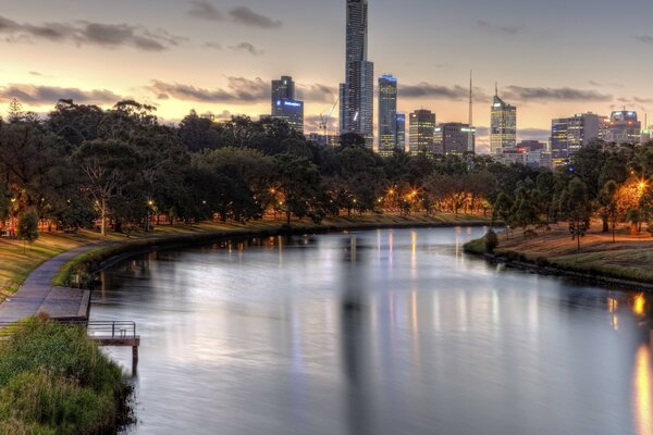 A river in the middle of a city park against the backdrop of skyscrapers