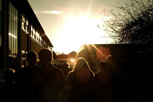 Dunkle Silhouetten von Menschen auf dem Hintergrund der Sonne