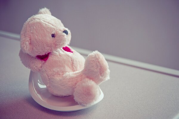 A miniature bear cub rests on a saucer