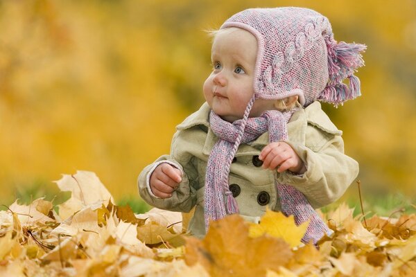 Bambino che gioca foglie nel parco autunnale