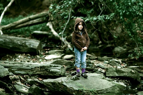 The child stands in the forest and looks into the distance