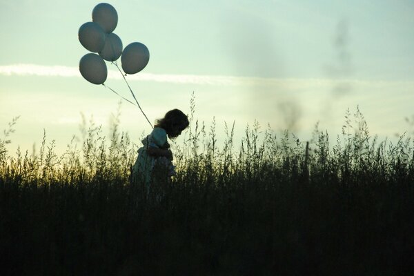 A girl with balloons at sunset