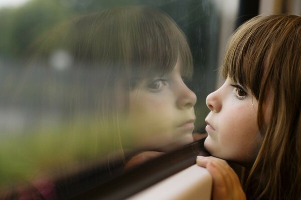 Das Kind schaut in ein reflektierendes Fenster