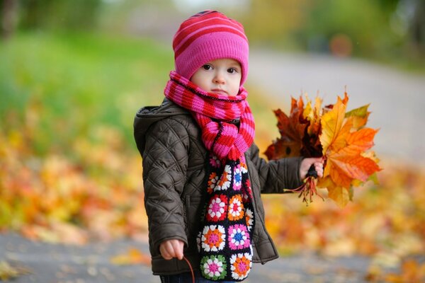 Baby im Herbst mit einem Blumenstrauß aus Blättern