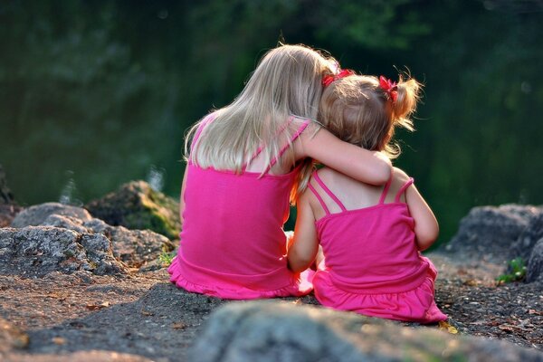 Die Kinder umarmen und verschweigen sich vor dem Hintergrund der Natur